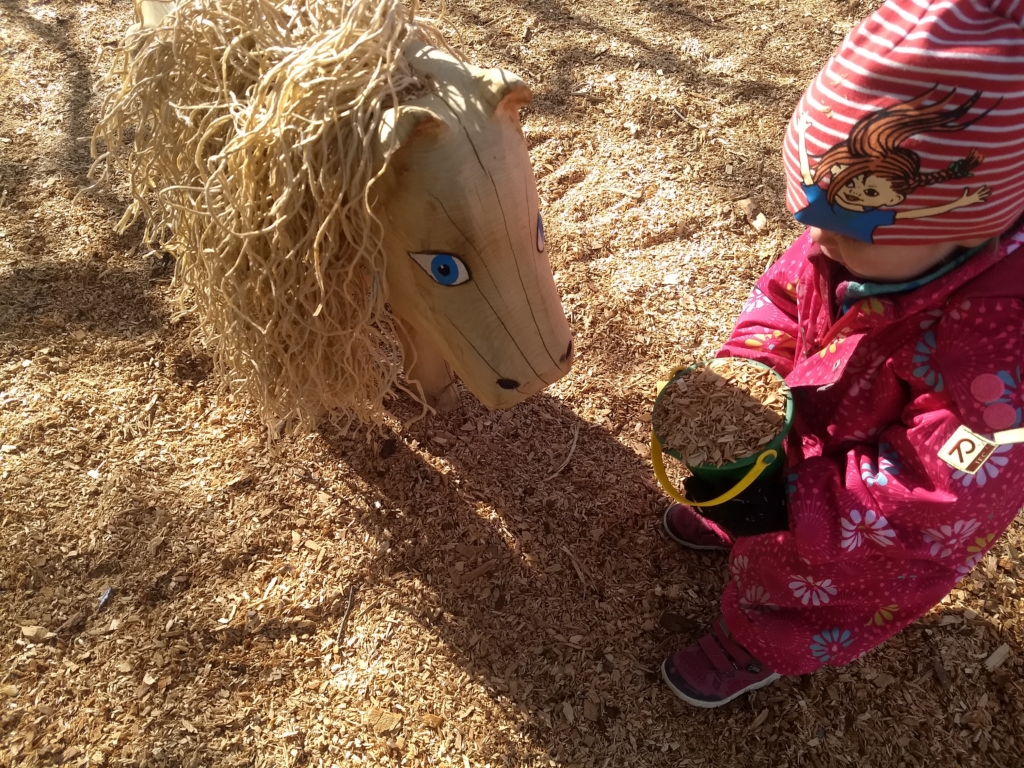 Ett barn leker med en häst av trä i parkleken RInken