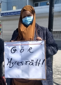 En kvinna med munskydd håller en skylt med texten Gör hyresrätt